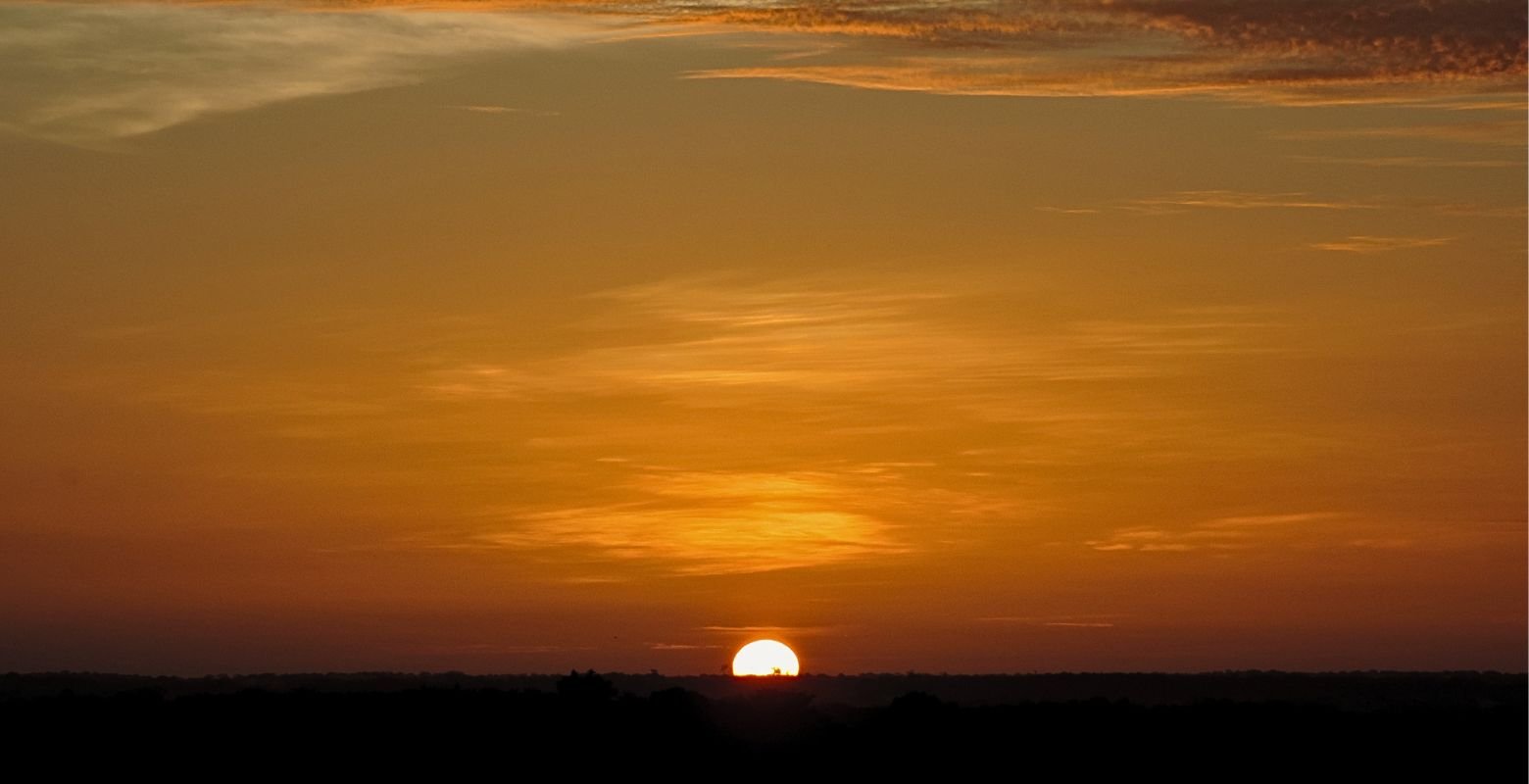 Amanecer llanero en La Macarena, Meta, con el sol iluminando el horizonte de los Llanos Orientales durante una experiencia de naturaleza.