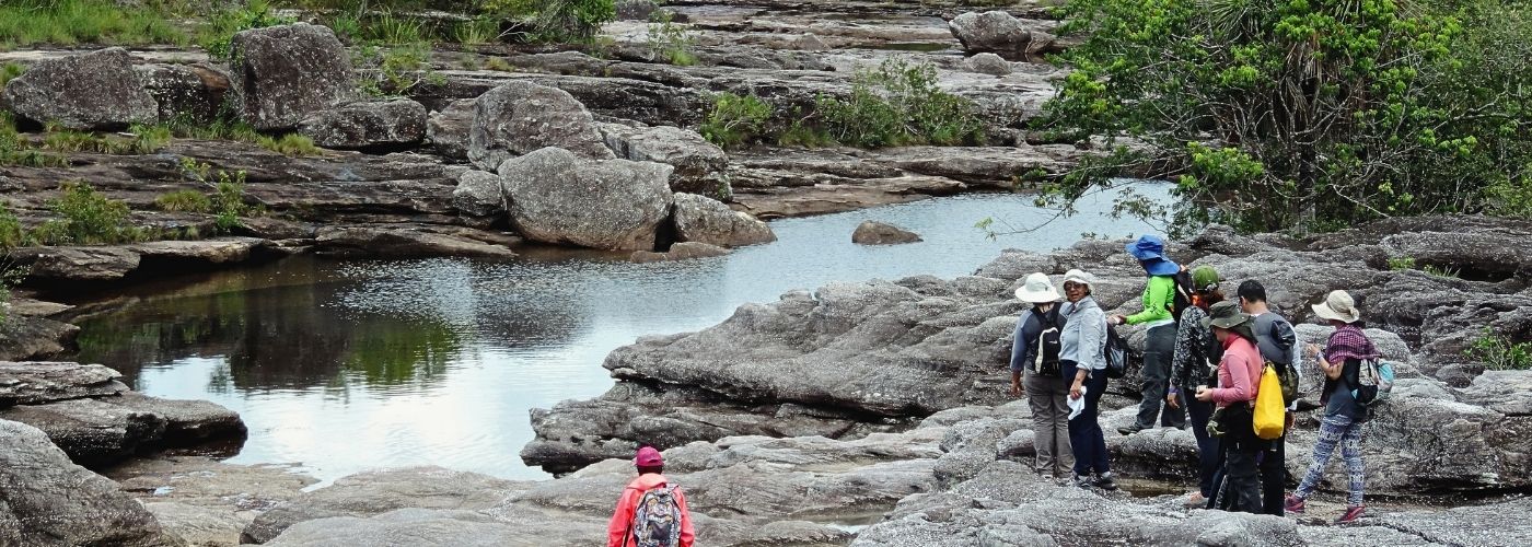 Excursionistas recorriendo las formaciones rocosas de Caño Cristales durante un tour en la Sierra de La Macarena, Meta, Colombia.