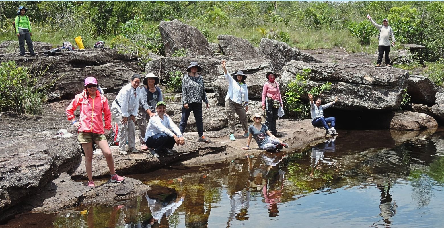 Viajeros disfrutando un pozo cristalino de Caño Cristales entre formaciones rocosas y paisajes naturales de La Macarena, Meta.